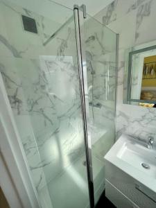 a white bathroom with a shower and a sink at Appartement vue Saint Joseph in Le Havre