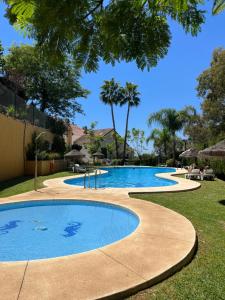 una gran piscina en un patio con árboles en Semi-detached beachfront villa Benalmadena-Costa, en Benalmádena