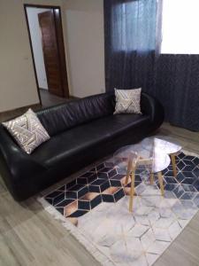 a black leather couch in a living room with a table at Residence Eliz in Kabrousse