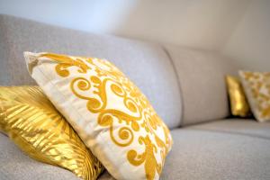 a couch with two gold pillows on it at Le GoldenLeaf - Netflix/Wi-Fi Fibre - Séjour Lozère in Mende +33 photos