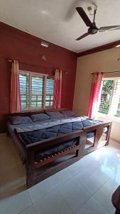 a large bed in a room with a ceiling fan at Blue Petal Homestay in Virajpet