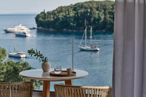 a table with a glass of wine and two chairs at San Antonio Corfu Resort (Adults Only) in Kalami