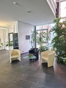 a lobby with chairs and a table and plants at Green Night in Falkenstein