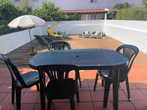 een tafel en stoelen en een parasol op een patio bij Casa do Almograve in Odemira