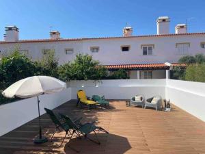 a patio with chairs and an umbrella and a building at Casa do Almograve in Odemira