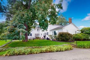 a white house with a tree in the yard at Benton Farmhouse in Penn Yan