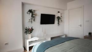 a white bedroom with a desk and a tv on the wall at Central View Calimanesti in Călimăneşti