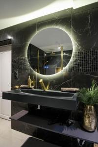 La salle de bains est pourvue d'un lavabo noir et d'un miroir. dans l'établissement La Golden Suite, à Cambrai