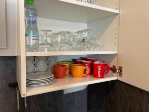 a cupboard filled with cups and plates and glasses at Apartament Wypoczynek Nowoczesna Malta Parking GoldAir in Poznań +19 photos