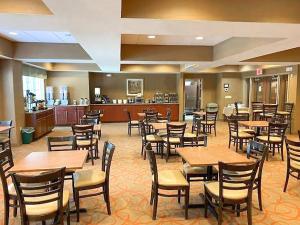 a restaurant with wooden tables and chairs and a kitchen at Palm Coast Hotel & Suites-I-95 in Palm Coast