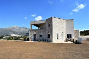 a large stone building in a field with a mountain at Smailis apartment 2 in Lygourio