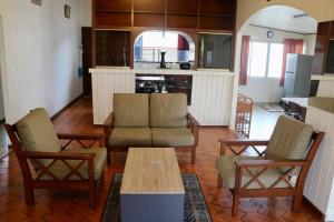 uma sala de estar com cadeiras e uma mesa e uma cozinha em Faatau House 3 bedrooms and big living room em Papeete