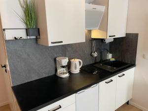 cocina con armarios blancos y encimera negra en Apartament Wypoczynek Nowoczesna Malta Parking GoldAir, en Poznan