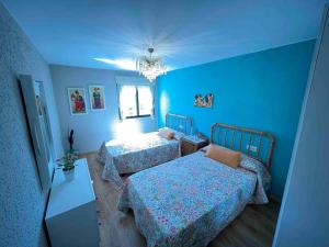 a blue bedroom with two beds and a chandelier at Medulillas 2 A solo 2000 m de Las Médulas in Yeres