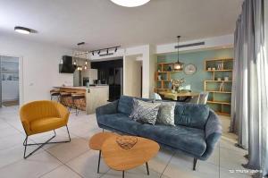 a living room with a blue couch and a kitchen at Beachfront Sea View Dream Escape - 3BR with Mamad in Nahariyya