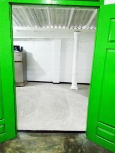 a green door opening to a room with a white wall at Green Bird in Mirissa