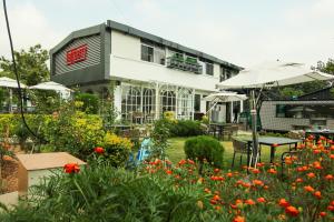 a house with a garden with flowers in front of it at Kaffberry Cafe & Homestays in Kūd