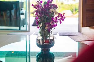 un jarrón lleno de flores púrpuras sentado en una mesa en Villa Stella 16 Santi Thani Maenam, en Nathon Bay