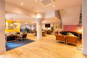 uma sala de estar com sofás, mesas e cadeiras em Holiday Inn Cardiff City, an IHG Hotel em Cardiff