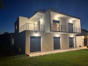 Casa blanca grande con balcón por la noche en VILLA LENA, en Sainte-Geneviève-des-Bois