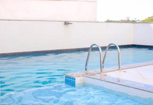 uma piscina de água azul e barras de metal em Axé home - Apartamento conceito em Salvador em Salvador