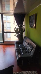 un sofá de cuero negro en una habitación con una pared verde en Apartamento Conjunto Residencial Yerbabuena, en Soacha
