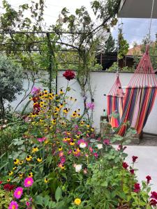 a garden with flowers and two hanging hammocks at Guest House PIROSMANI in Tsqnetʼi