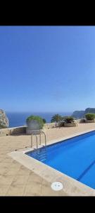 a blue swimming pool with the ocean in the background at Cumbre Moraig in Benitachell