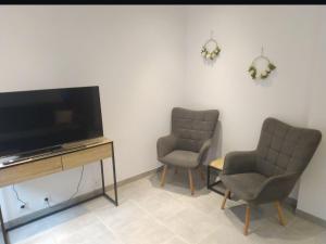 ein Wohnzimmer mit 2 Stühlen und einem Flachbild-TV in der Unterkunft Chez Bruno in Rothau