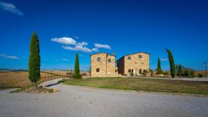 an old stone building on a field with cypress trees at Podere Fossaccio Casa Fiordaliso in Asciano