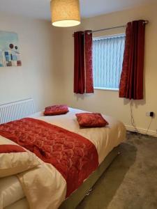 a bedroom with a bed with red pillows on it at Droitwich Spa centre apartment in Droitwich