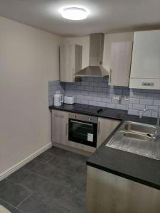 a kitchen with a sink and a stove top oven at Droitwich Spa centre apartment in Droitwich