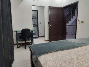 a bedroom with a bed and a desk and a chair at Fully Serviced Holiday Home Near Lahore Ring Road in Lahore