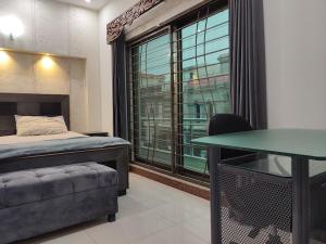 Schlafzimmer mit einem Bett, einem Tisch und einem Fenster in der Unterkunft Fully Serviced Holiday Home Near Lahore Ring Road in Lahore