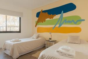 2 camas en una habitación con un mural en la pared en Fliphaus Nicaragua 5900 - 5 Bd Pool & Bbq en Buenos Aires