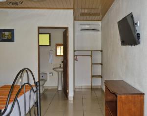 a room with a bathroom with a sink and a television at Hotel D'Lucia - Quebrada Ganado, Jaco, Costa Rica in Puntarenas