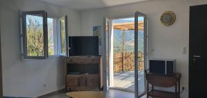uma sala de estar com uma televisão e uma porta de vidro deslizante em Vue de rêve em Calcatoggio