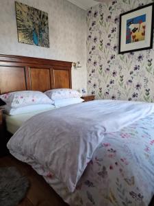 a bedroom with a bed with white sheets and floral wallpaper at Isla Rose Cottage in Blairgowrie