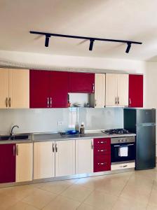uma cozinha com armários e electrodomésticos vermelhos e brancos em Eden Home em Durrës