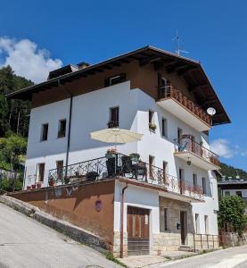 a white building with a balcony and an umbrella at Villa Vittorio in Forno di Zoldo