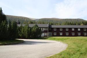 un gran edificio con una carretera delante en Dovreskogen Gjestegård AS, en Dovreskogen