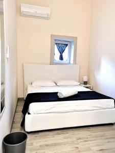 un lit blanc dans une chambre avec une fenêtre dans l'établissement Dietro Piazza Duomo, à Acireale