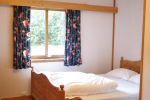 a bed in a bedroom with a window with curtains at Dovreskogen Gjestegård AS in Dovreskogen