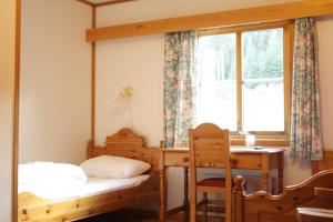 a bedroom with two beds and a desk and a window at Dovreskogen Gjestegård AS in Dovreskogen