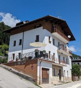 a white building with a balcony and an umbrella at Appartement Il Gallo in Forno di Zoldo