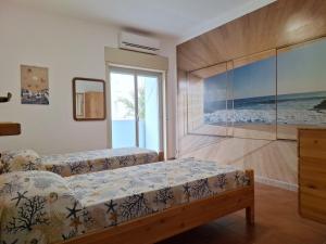 a bedroom with two beds and a large window at Maria's - Parking Area, no ZTL, close Train Station and Beach in Cefalù