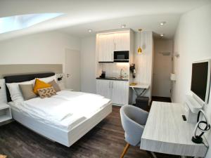 1 Schlafzimmer mit einem weißen Bett und einer Küche in der Unterkunft AlpenOase - Schliersee in Schliersee