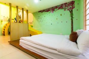 a bedroom with a bed with a tree mural on the wall at Chiuan Jia Hot Spring Homestay in Jiaoxi