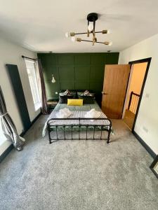 a bedroom with two beds and a green wall at THE SOUTH VALLEY HOME in Neath