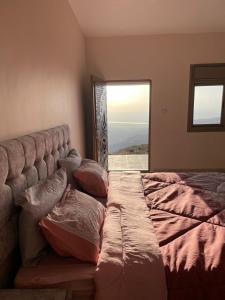um quarto com uma cama com almofadas e uma janela em مزرعة الشفق em Ad Dimnah